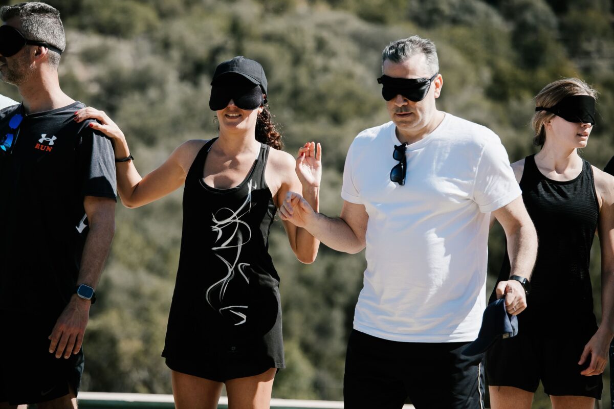 Group of people participating in a blindfolded team-building activity outdoors