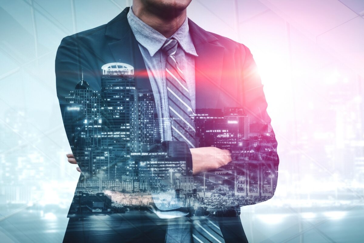 Businessman with crossed arms superimposed over a cityscape